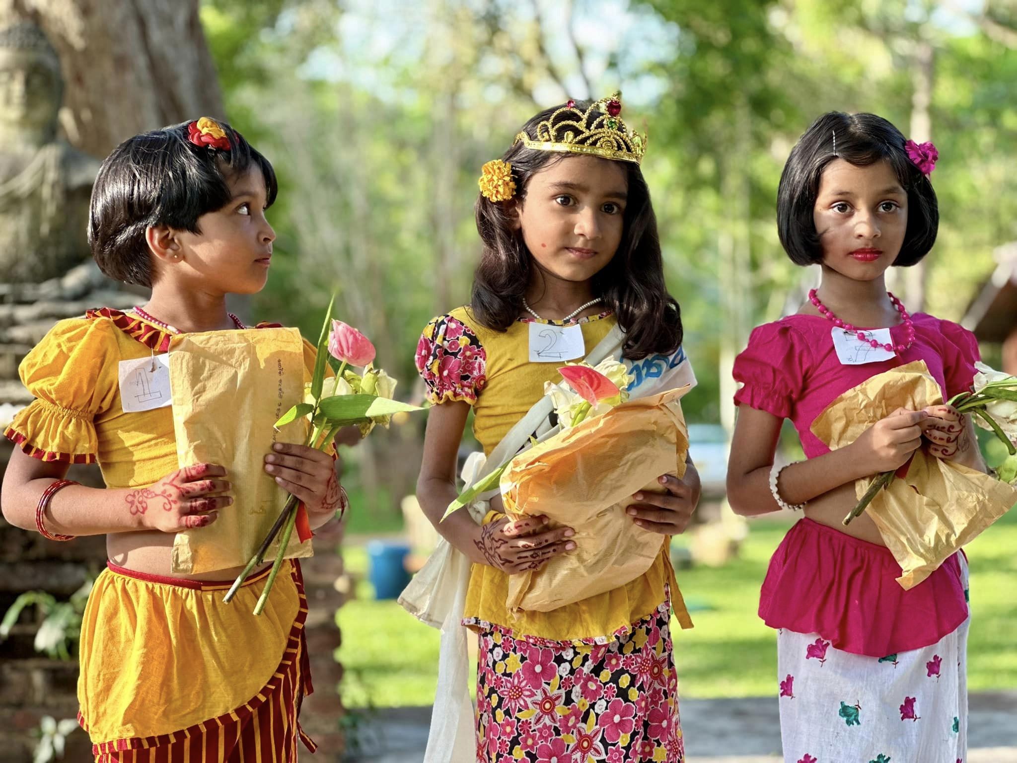 Bambine con fiori e regali in mano durante un festival in Sri Lanka.