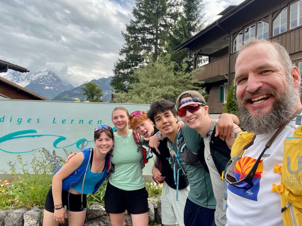 Gruppo di persone sorridenti davanti a un edificio di montagna.