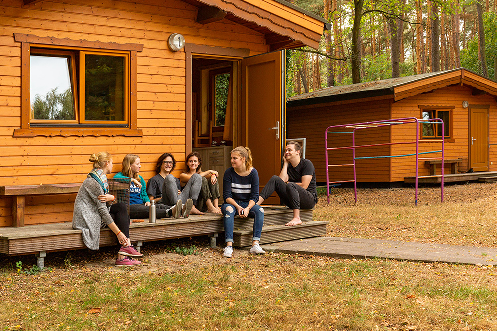 Gruppo di amici seduto su una pedana di legno davanti a un cottage.