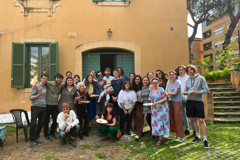 Un gruppo di persone sorridenti in piedi davanti a una casa accogliente.