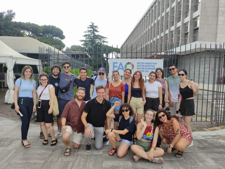 Un gruppo di persone sorride mentre posa per una foto davanti a un edificio.