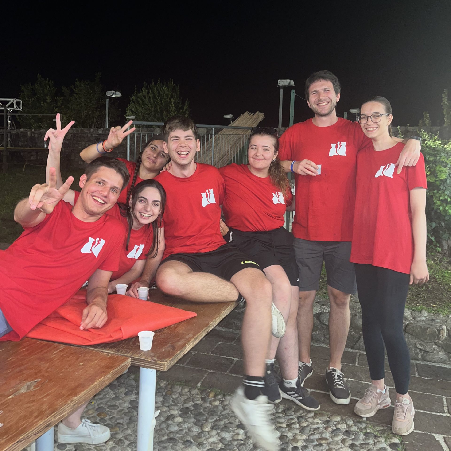 Gruppo di persone con magliette rosse a una festa all'aperto di notte.