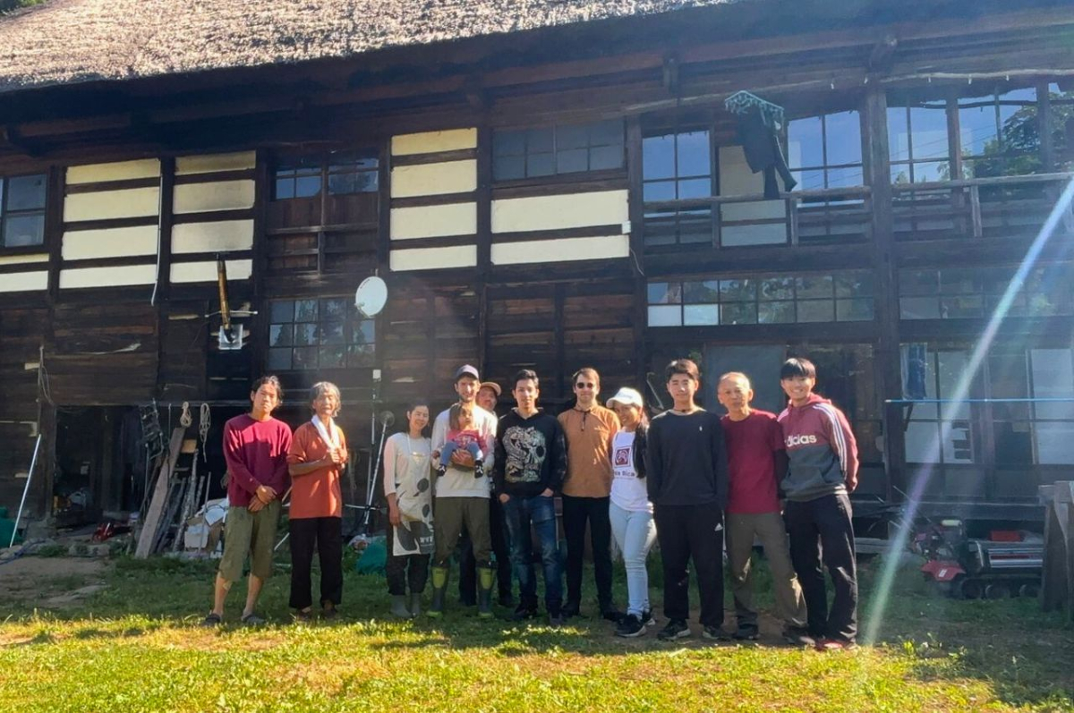 Partecipanti sorridenti davanti a un’abitazione giapponese in legno